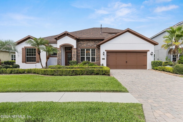 view of front of house with a front yard, a garage, stone siding, and stucco siding