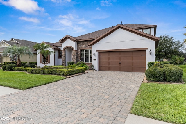 view of front of home with a front lawn, stone siding, decorative driveway, stucco siding, and an attached garage