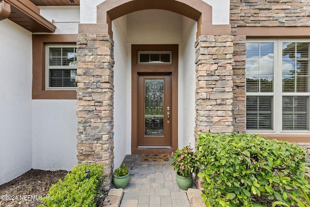 property entrance with stone siding and stucco siding
