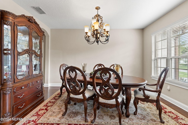 dining room featuring dark wood-type flooring, baseboards, a notable chandelier, and visible vents