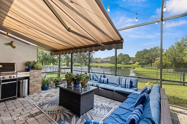 view of patio featuring a water view, a fenced backyard, an outdoor kitchen, outdoor lounge area, and a grill