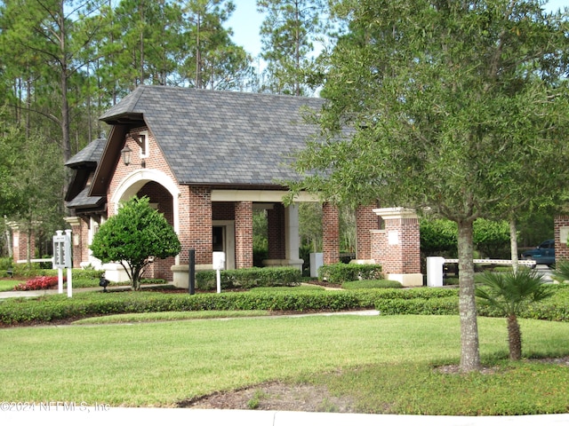 english style home with brick siding and a front lawn