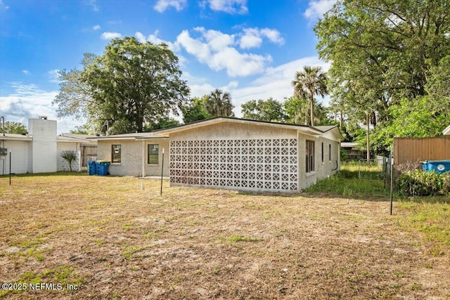 rear view of property featuring fence and a yard