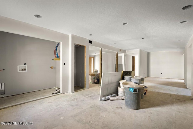unfurnished living room featuring a textured ceiling and unfinished concrete flooring