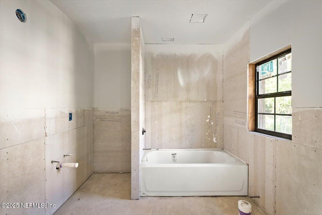 bathroom featuring tile walls, concrete floors, and a bath
