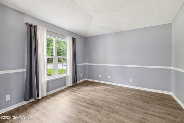 spare room featuring baseboards, a textured ceiling, and wood finished floors