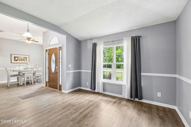 foyer entrance featuring baseboards, a ceiling fan, wood finished floors, and lofted ceiling