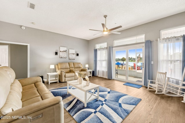 living area featuring a ceiling fan, a textured ceiling, visible vents, and wood finished floors