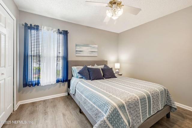bedroom with baseboards, a textured ceiling, ceiling fan, and wood finished floors