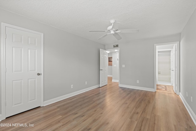 unfurnished bedroom featuring light wood-style flooring, a textured ceiling, baseboards, ceiling fan, and connected bathroom
