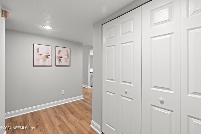corridor with light wood-style flooring, baseboards, and recessed lighting