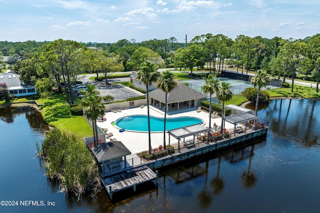 community pool featuring a patio, fence, a water view, and view of scattered trees