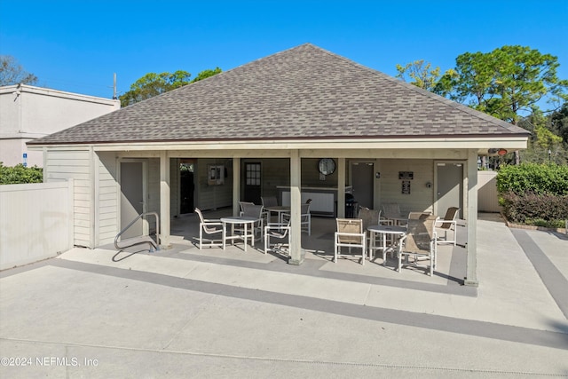 rear view of property featuring a shingled roof, fence, and a patio