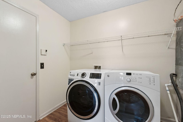 laundry room featuring laundry area, a textured ceiling, washing machine and clothes dryer, wood finished floors, and baseboards