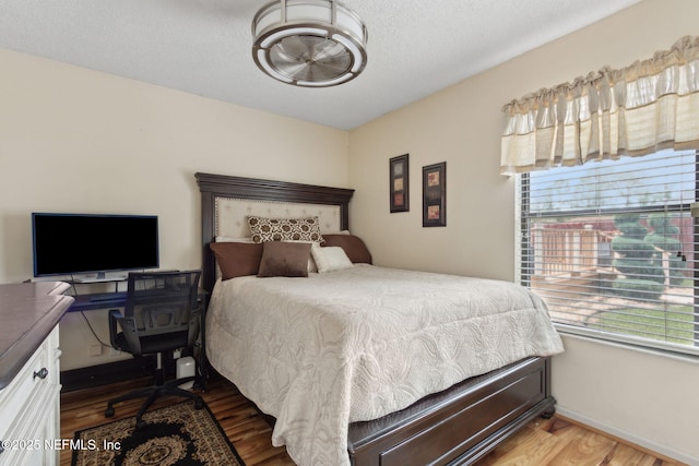 bedroom with baseboards, multiple windows, and wood finished floors