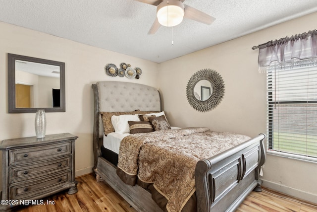 bedroom featuring baseboards, a textured ceiling, and wood finished floors