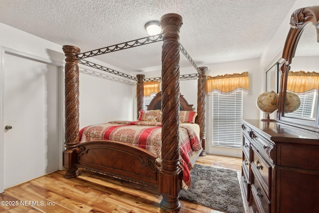 bedroom featuring multiple windows, a textured ceiling, and wood finished floors