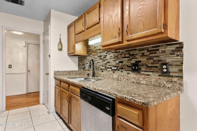 kitchen featuring a sink, light tile patterned floors, tasteful backsplash, stainless steel dishwasher, and visible vents
