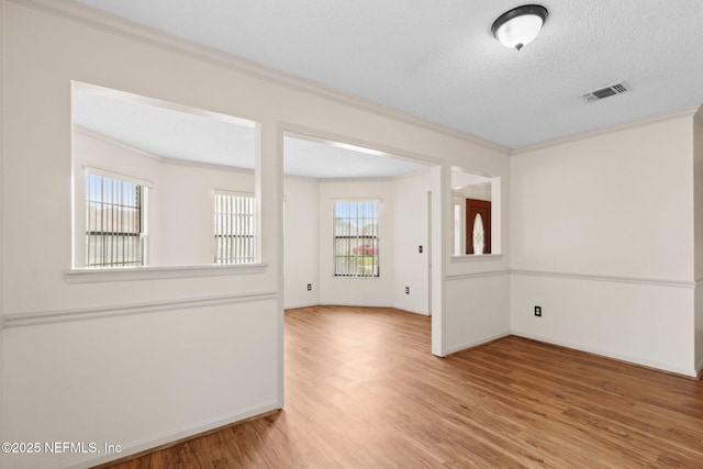 unfurnished room featuring crown molding, baseboards, wood finished floors, and visible vents