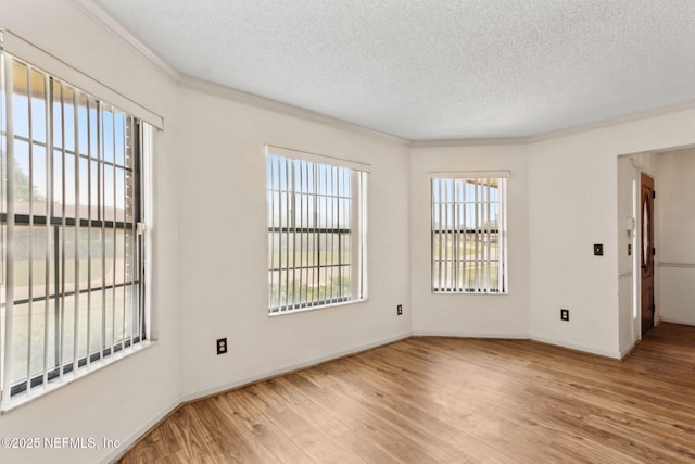 unfurnished room with baseboards, ornamental molding, a textured ceiling, and wood finished floors