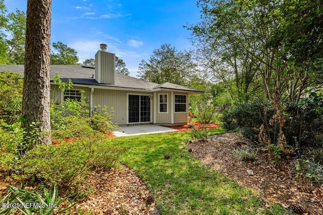 11598 Lazy Willow Ln, Jacksonville, FL 32223 - rear view of house with a patio, a chimney, a lawn, and roof with shingles