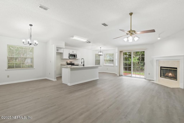 11598 Lazy Willow Ln, Jacksonville, FL 32223 - unfurnished living room featuring a chandelier, wood finished floors, baseboards, a premium fireplace, and a textured ceiling