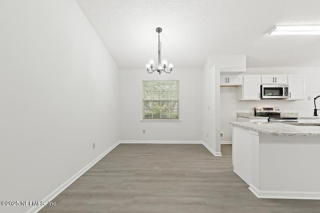 11598 Lazy Willow Ln, Jacksonville, FL 32223 - kitchen featuring appliances with stainless steel finishes, a textured ceiling, a chandelier, light wood-style flooring, and white cabinets