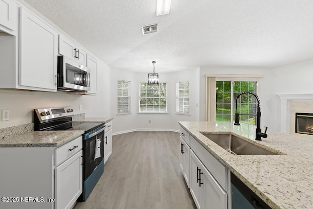 11598 Lazy Willow Ln, Jacksonville, FL 32223 - kitchen featuring stainless steel appliances, a sink, white cabinetry, light wood-type flooring, and a textured ceiling