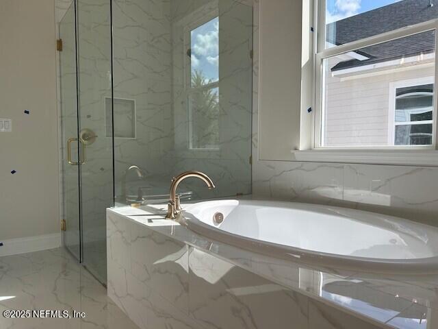 bathroom featuring plenty of natural light, marble finish floor, a bath, and a marble finish shower