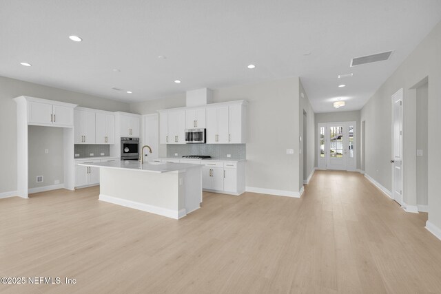 440 Slash Pine Pl, Yulee, FL 32097 - kitchen with appliances with stainless steel finishes, decorative backsplash, a center island with sink, white cabinetry, and recessed lighting