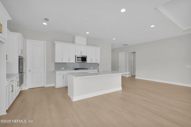 440 Slash Pine Pl, Yulee, FL 32097 - kitchen with stainless steel appliances, light wood-style flooring, a center island with sink, light countertops, and recessed lighting