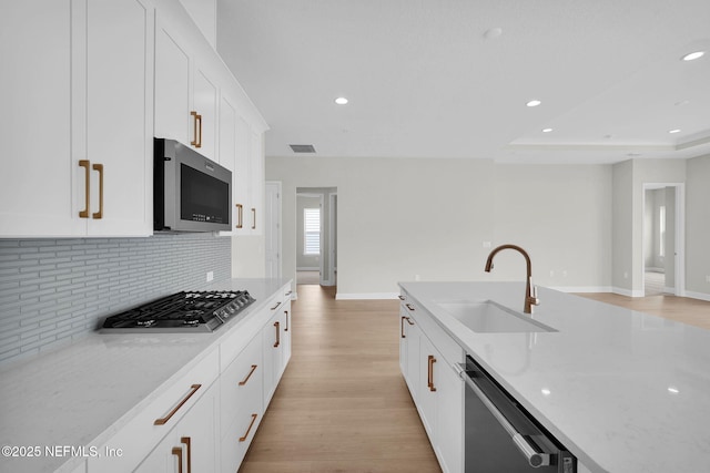 440 Slash Pine Pl, Yulee, FL 32097 - kitchen with stainless steel appliances, a sink, light wood-style flooring, backsplash, and light stone counters