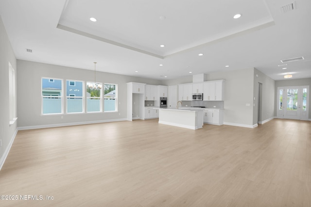 440 Slash Pine Pl, Yulee, FL 32097 - unfurnished living room featuring a tray ceiling, recessed lighting, baseboards, light wood-type flooring, and a chandelier