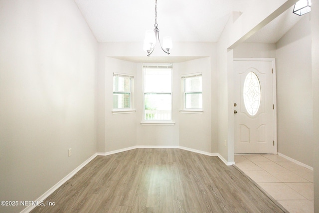 foyer entrance with baseboards, a chandelier, and wood finished floors