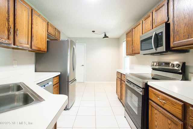 kitchen featuring light countertops, stainless steel appliances, brown cabinets, and light tile patterned flooring