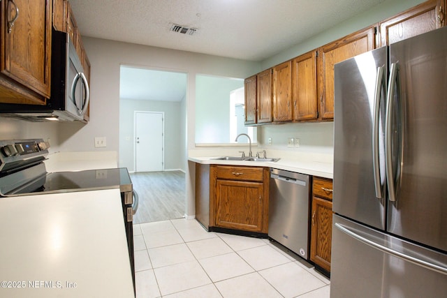 kitchen with light countertops, light tile patterned flooring, visible vents, a sink, and stainless steel appliances