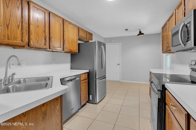 kitchen with brown cabinets, light countertops, appliances with stainless steel finishes, and a sink