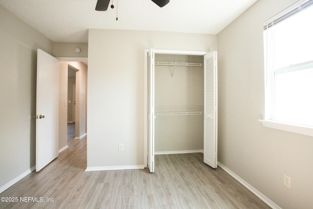 unfurnished bedroom featuring a closet, a ceiling fan, wood finished floors, and baseboards