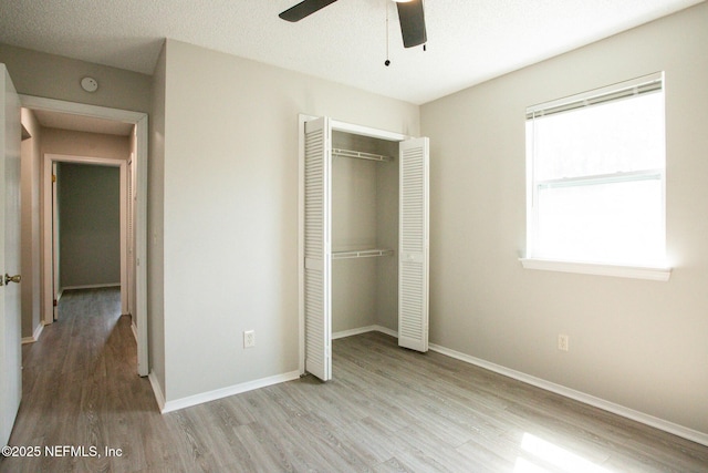 unfurnished bedroom featuring baseboards, a closet, a ceiling fan, and wood finished floors