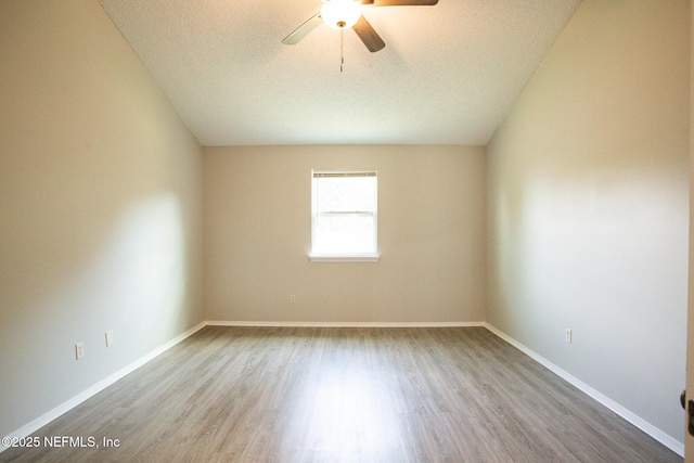 empty room with a textured ceiling, wood finished floors, baseboards, and ceiling fan