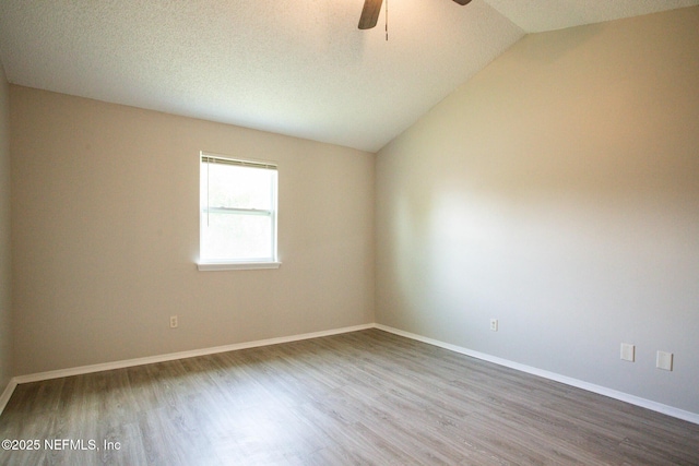 spare room featuring baseboards, vaulted ceiling, ceiling fan, and wood finished floors