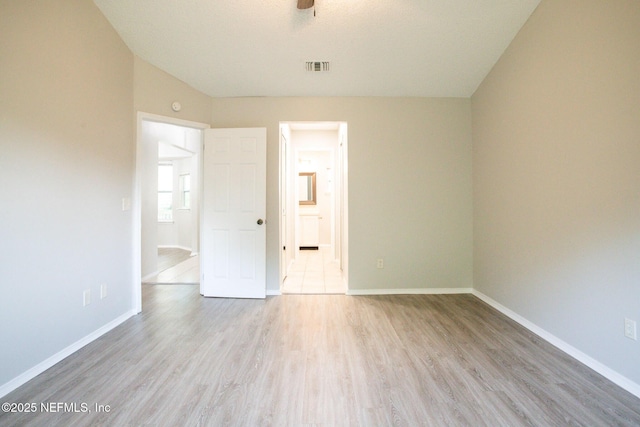 unfurnished bedroom with baseboards, light wood finished floors, connected bathroom, and visible vents