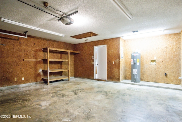 garage with electric water heater, visible vents, and a garage door opener