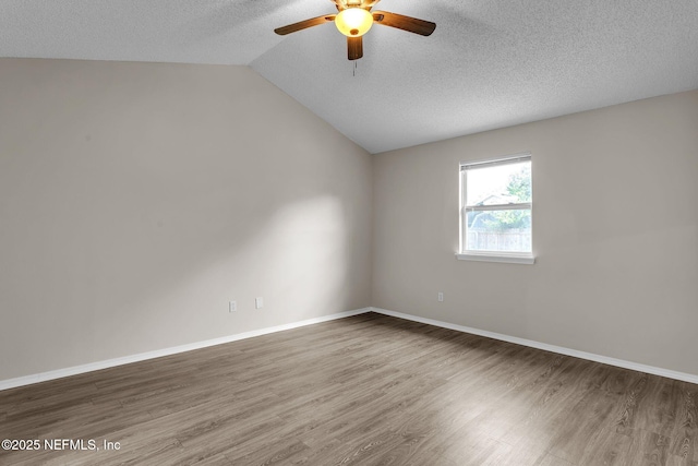 empty room with a textured ceiling, vaulted ceiling, wood finished floors, and ceiling fan