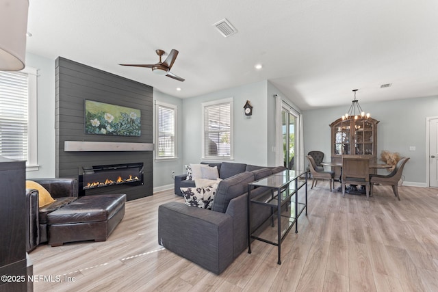109 Redbud Ln, Yulee, FL 32097 - living room featuring a fireplace, light wood-style floors, ceiling fan with notable chandelier, baseboards, and visible vents