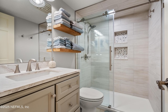 bathroom with vanity, a stall shower, and toilet