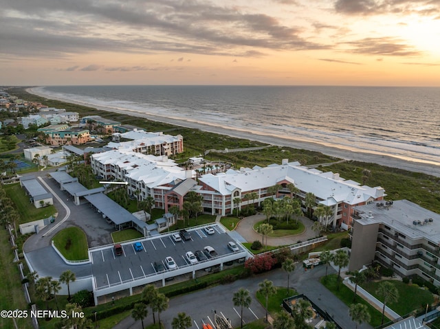 aerial view at dusk with a beach view and a water view