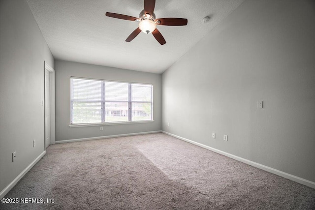 carpeted spare room with ceiling fan, baseboards, and lofted ceiling