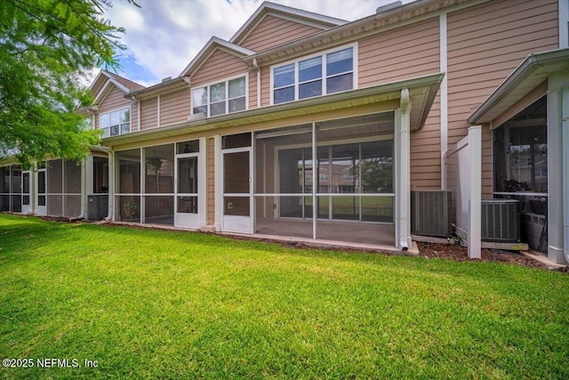 rear view of property with a yard, a sunroom, and central AC