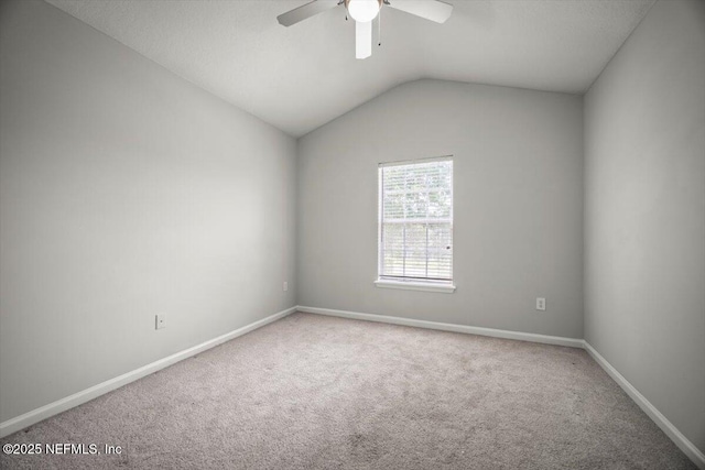 carpeted empty room with vaulted ceiling, baseboards, and a ceiling fan